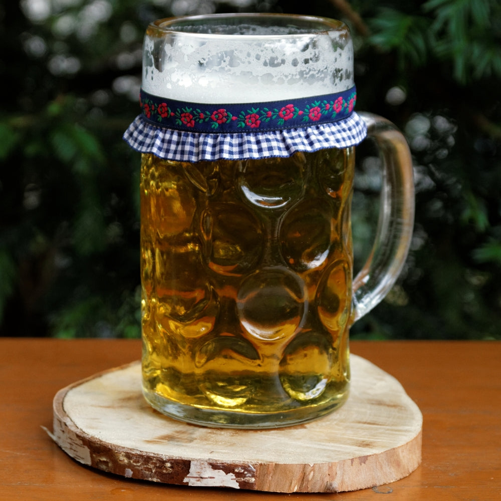 Ein mit Bier gefüllter Maßkrug mit Maßkrugband in Blau kariert mit Blumen