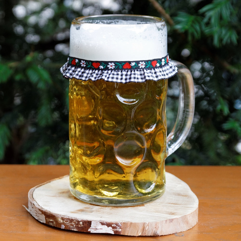 Ein mit Bier gefüllter Maßkrug mit Maßkrugband in Schwarz kariert mit roten Herzen