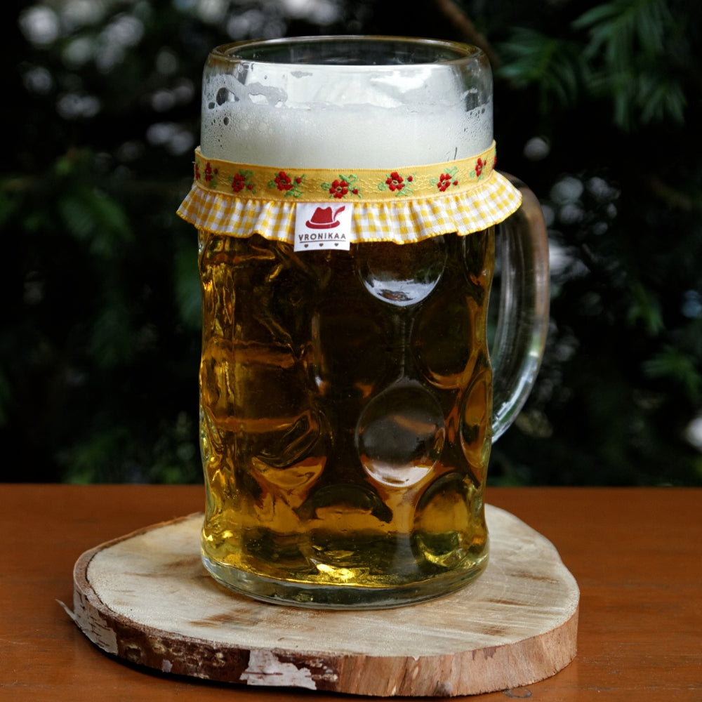Ein mit Bier gefüllter Maßkrug mit Maßkrugband in Gelb kariert mit Blumen