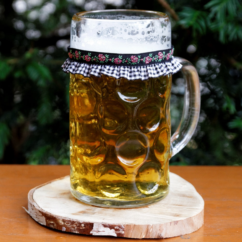 Ein mit Bier gefüllter Maßkrug mit Maßkrugband in Schwarz kariert mit Blumen