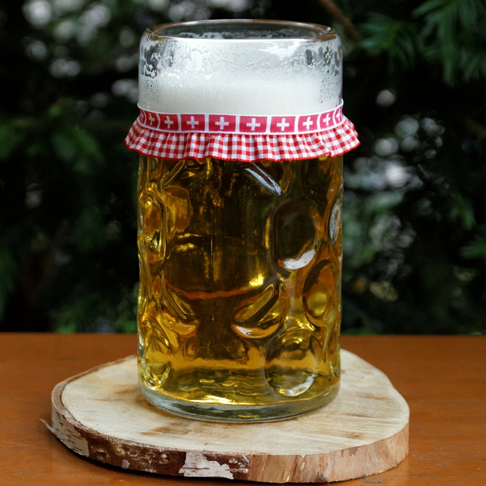 Mit Bier gefüllter Maßkrug mit Maßkrugband in Schweizer-Flagge