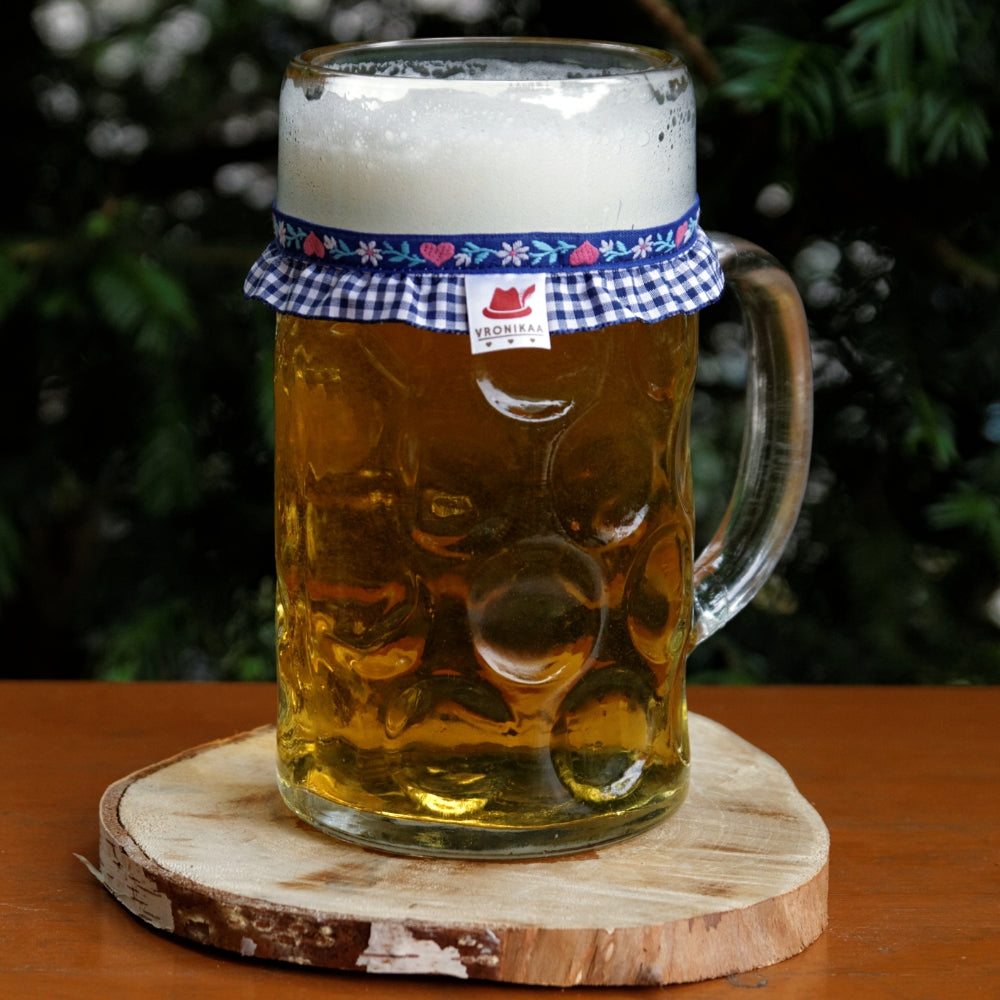 Ein mit Bier gefüllter Maßkrug mit Maßkrugband in Blau kariert mit rosa Herzen