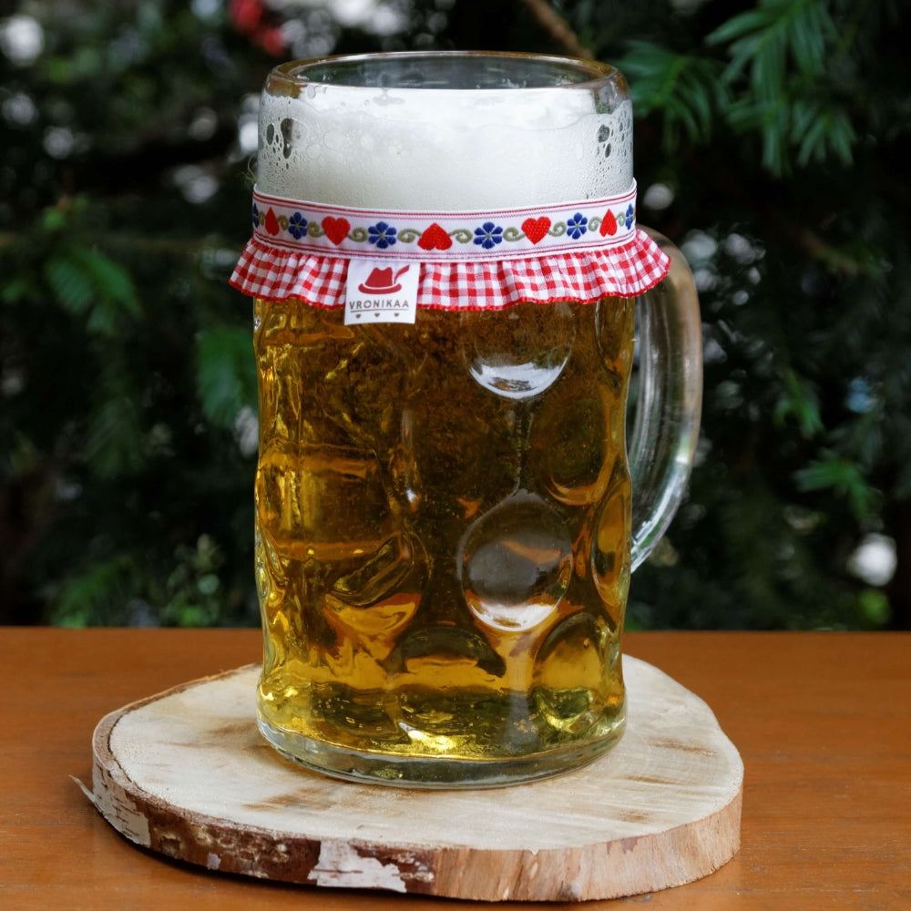 Ein mit Bier gefüllter Maßkrug mit Maßkrugband in Rot kariert mit roten Herzen und blauen Blumen by vronikaa