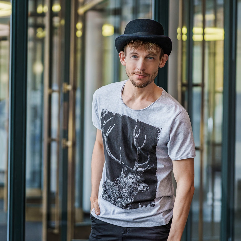 Herren Model trägt einen Zylinder und das Shirt Hirschgeweih zur Jeans