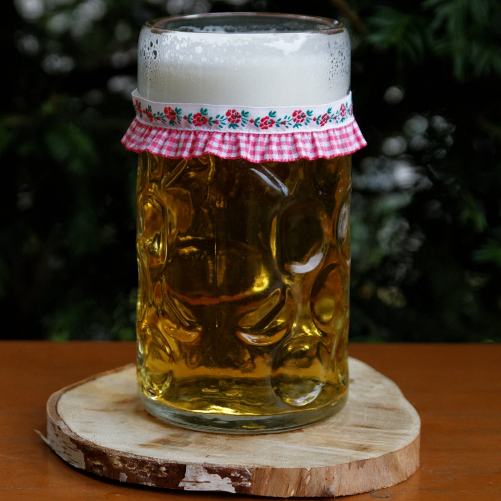 Ein mit Bier gefüllter Maßkrug mit Maßkrugband in Pink kariert mit Blumen