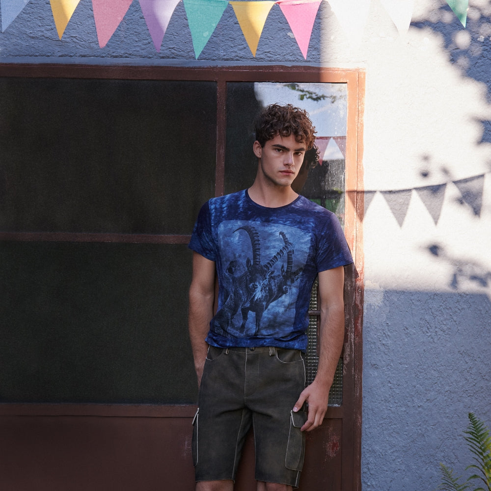 Mann in Lederhose und einem Blauen Batik Shirt