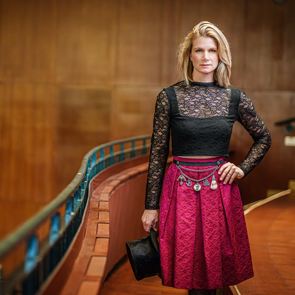 Model mit schwarzen Spitzen-Crop-Top und Trachtenrock mit Charivari-Gürtel