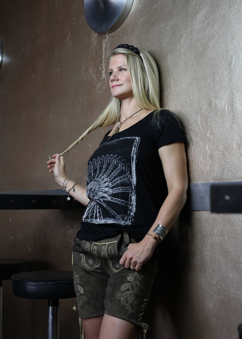 Frau trägt Shirt mit Riesenrad-Motiv und brauner Lederhose