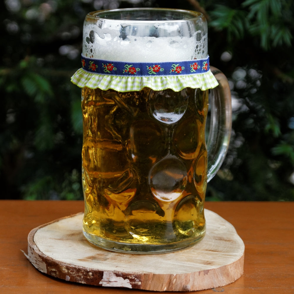 ein mit Bier gefüllter Maßkrug mit Maßkrugband in Grün kariert mit Blumen in Rot