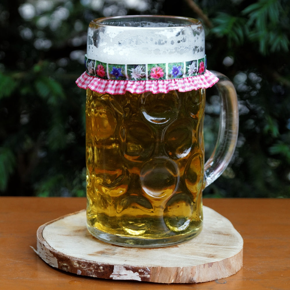 Mit Bier gefüllter Maßkrug mit Maßkrugband in Rosa mit Blumen