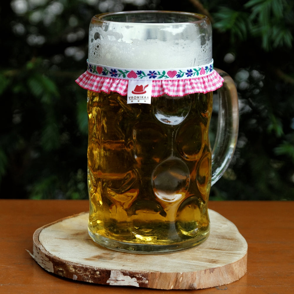 Ein mit Bier gefüllter Maßkrug mit Maßkrugband in rosa kariert mit rosa Herzen