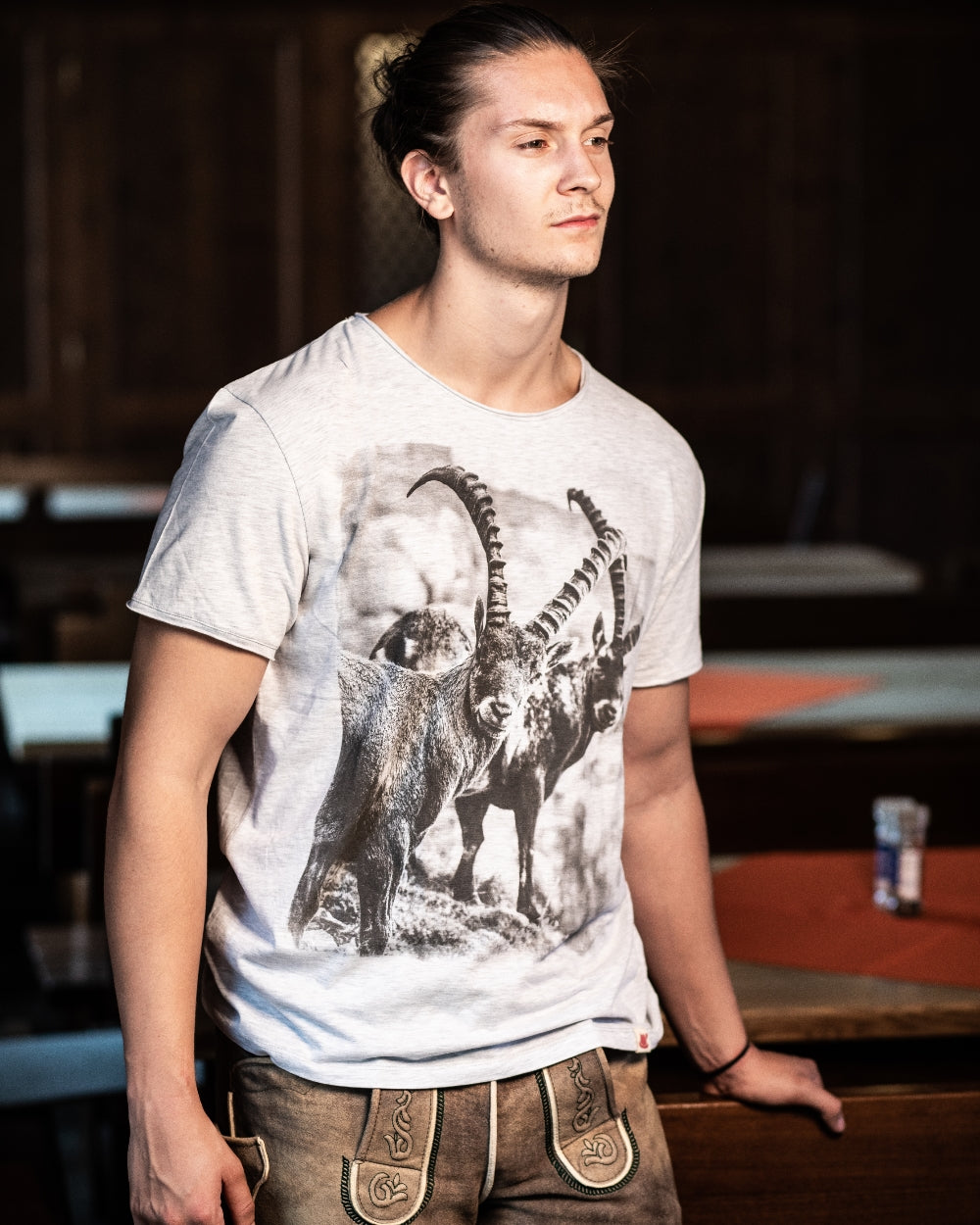 Model steht in Lederhose im Wirtshaus und hat das T-Shirt Steinböcke an